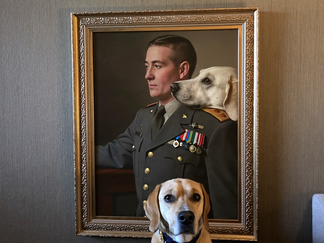 Hund sitzt stolz neben seinem royalen Uniform-Portrait an der Wohnzimmerwand