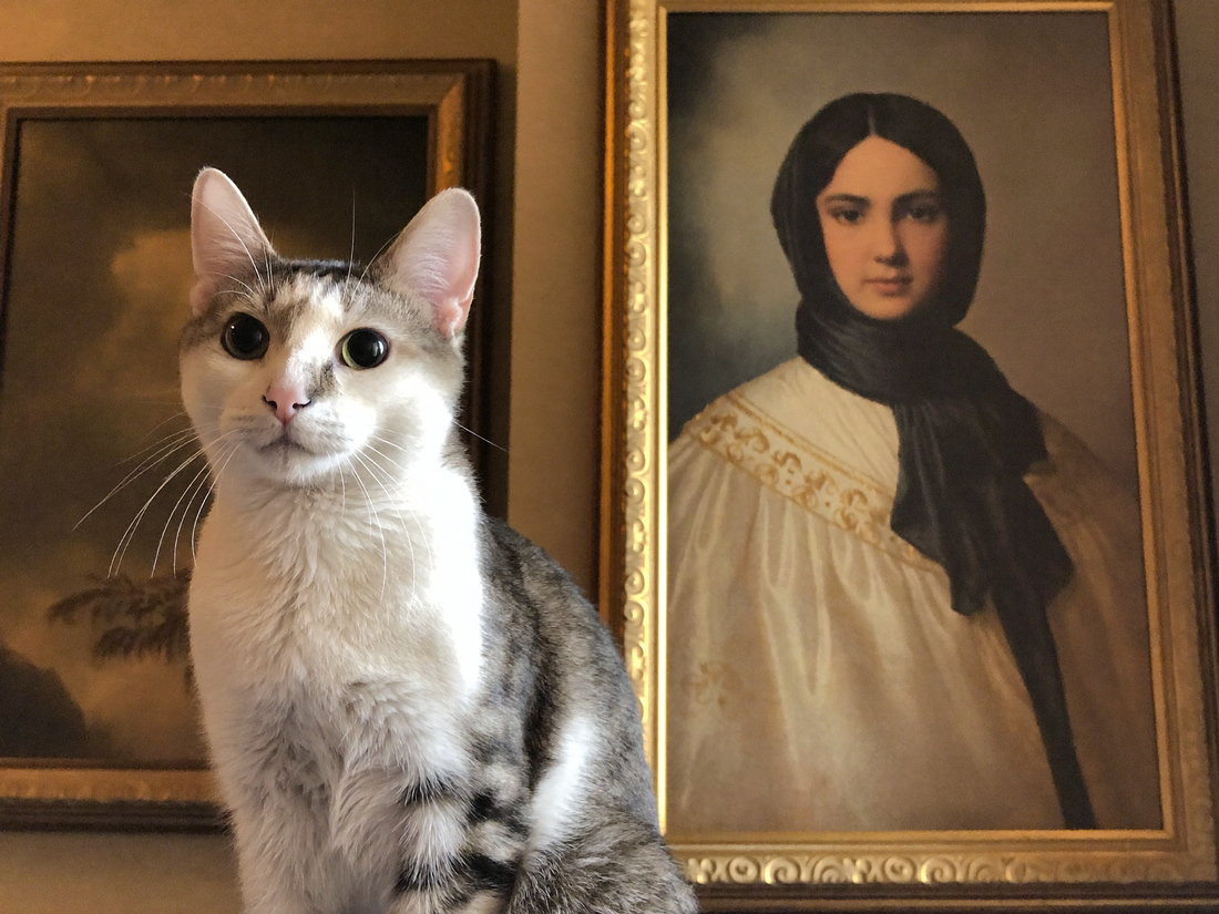 Katze sitzt stolz neben ihrem royalen Mona-Lisa-Portrait als Leinwand im Wohnzimmer