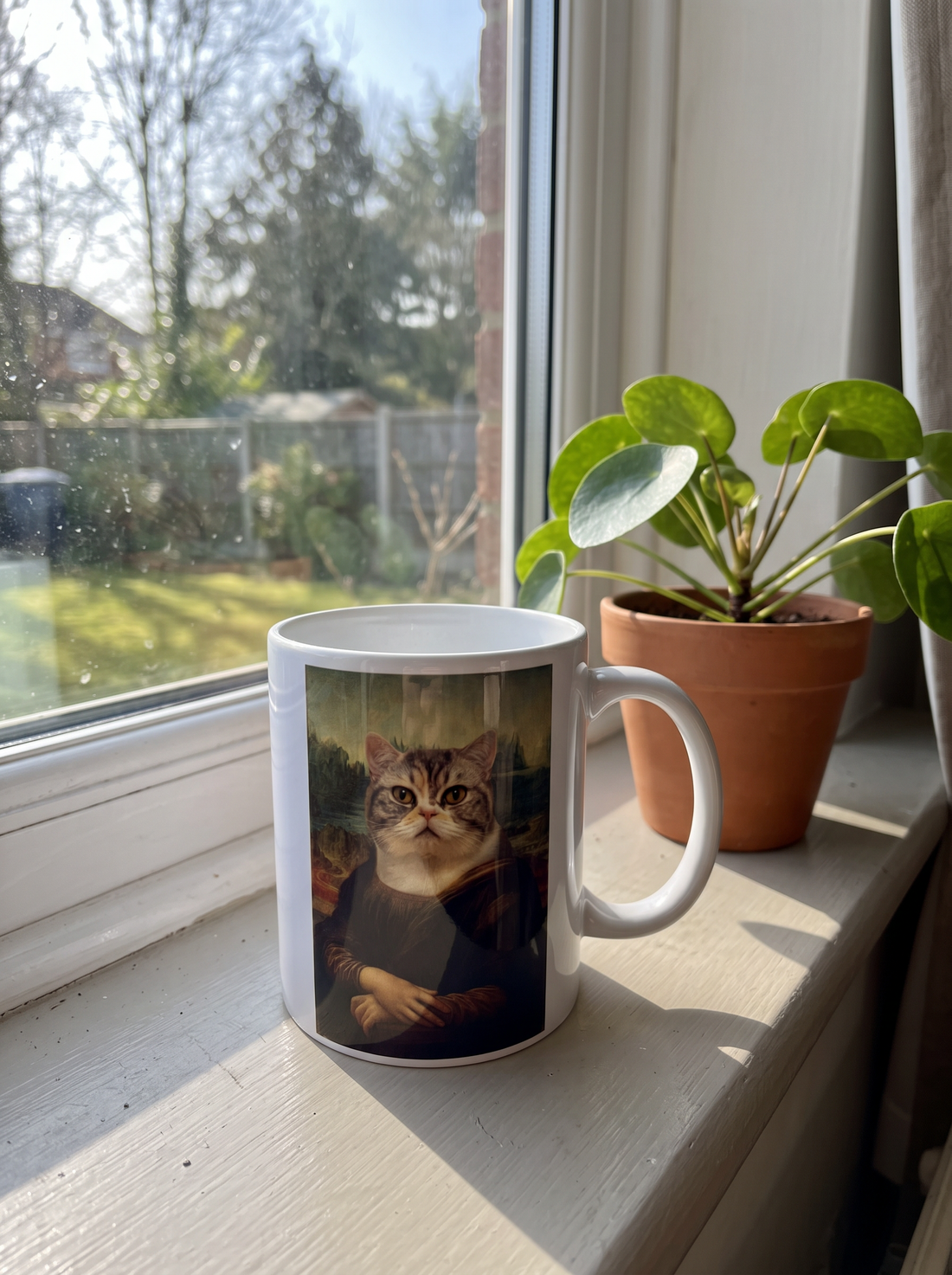 Katzentasse Mona Lisa auf der Fensterbank neben einer Pflanze